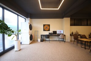 Un espacio de oficina moderno con un escritorio, dos sillas, una computadora y un ventanal grande.