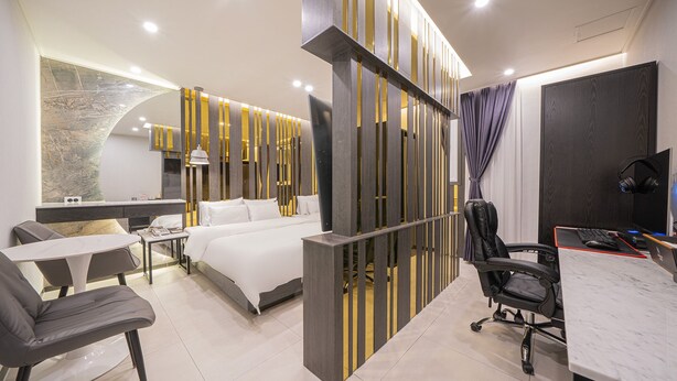 Una habitación de hotel moderna con cama, escritorio, sillas y televisión.