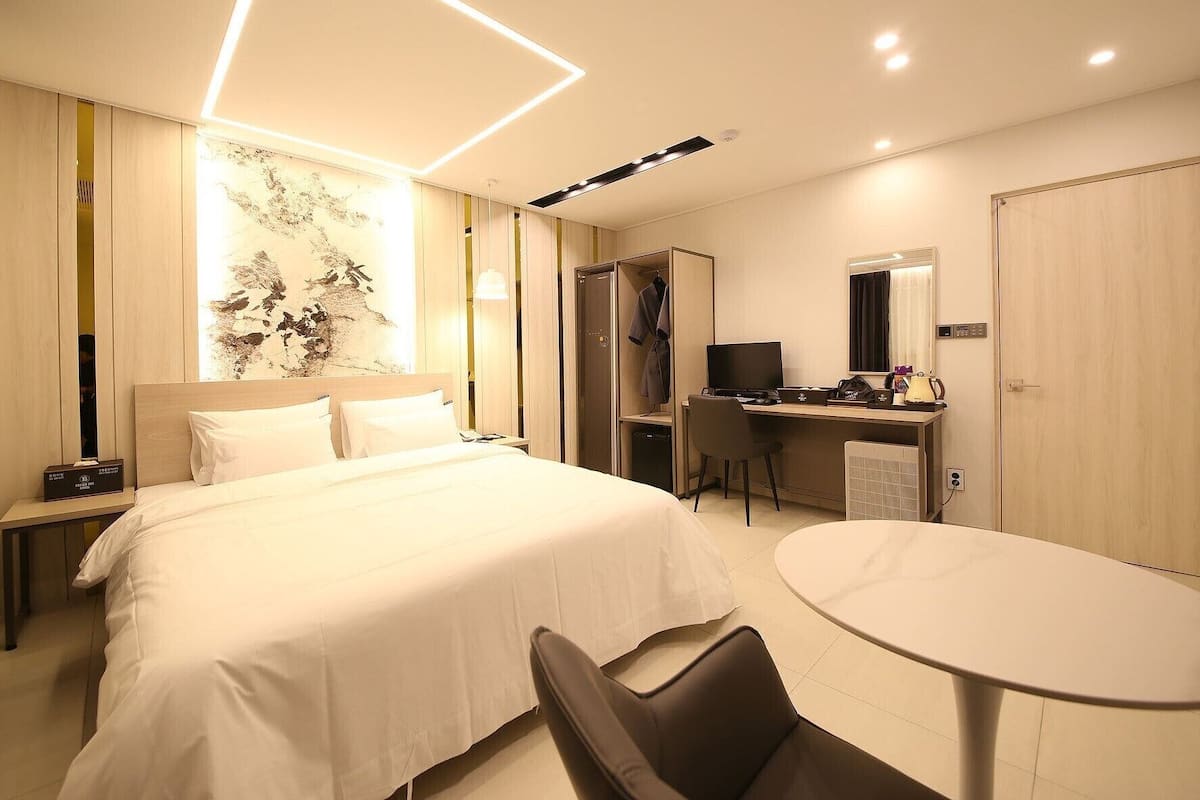 Una habitación de hotel con cama, escritorio, silla y una mesa redonda.