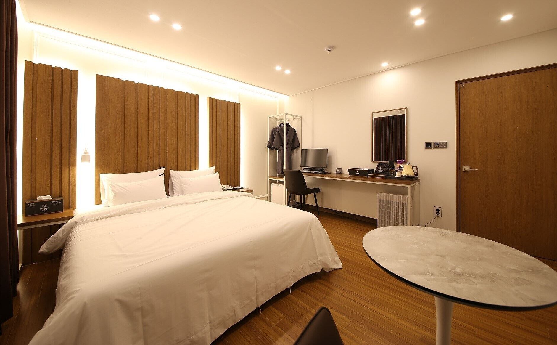 Een hotelkamer met een groot bed, een bureau met een computer, een stoel, een tafeltje en een kledingkast.