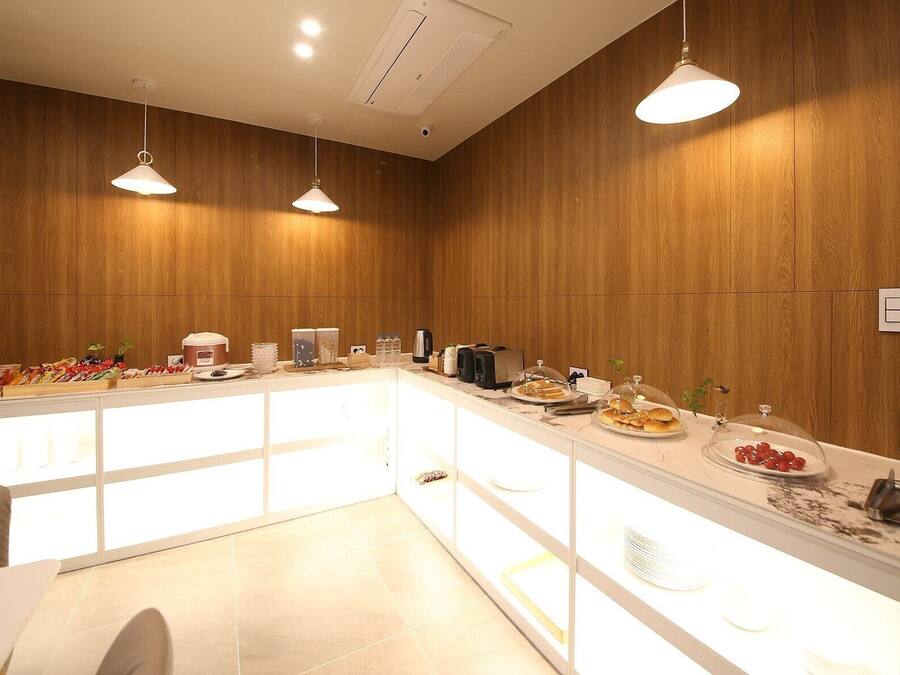 A modern breakfast bar with wooden paneling, pendant lighting, and a variety of breakfast items.
