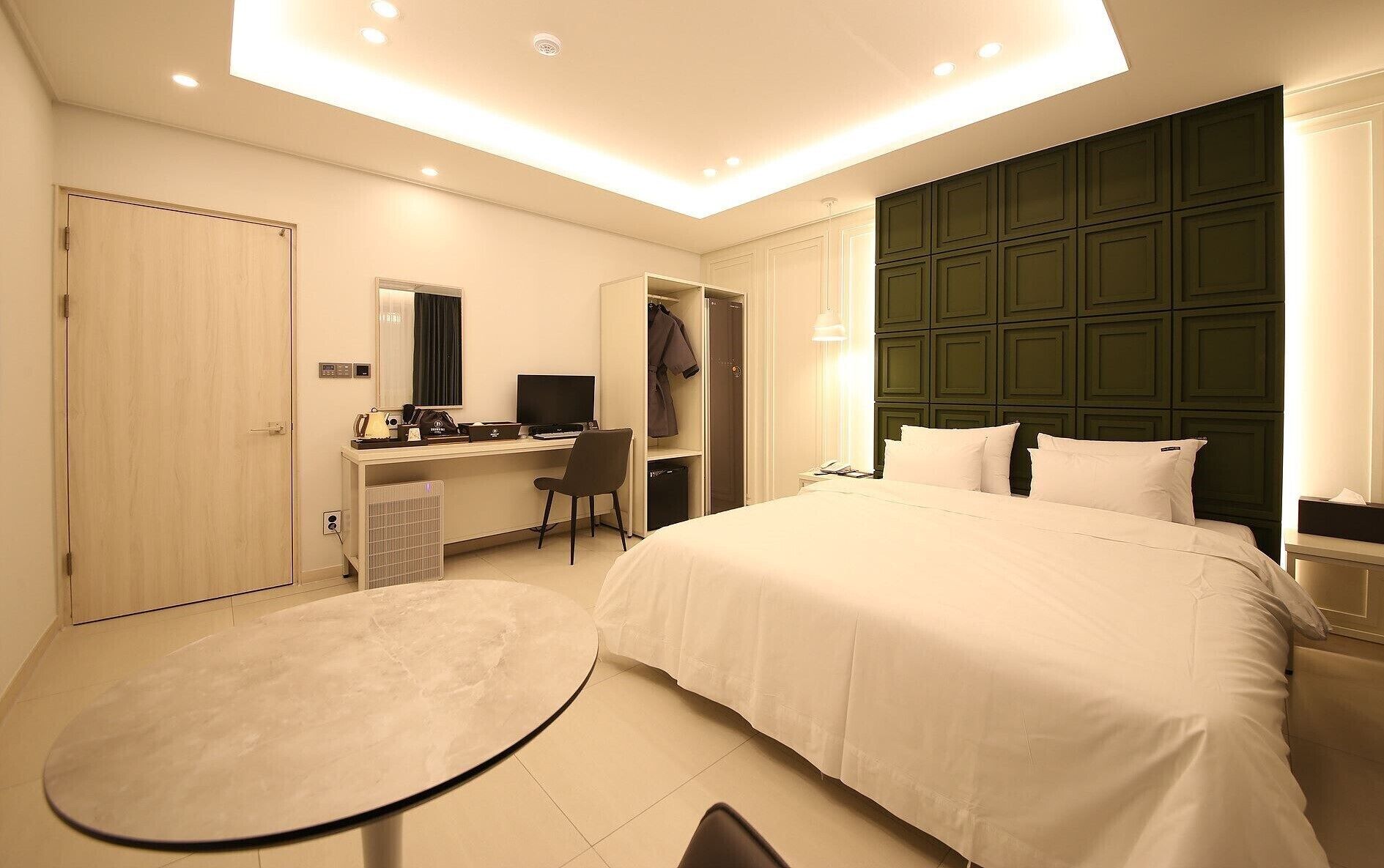 A hotel room with a bed, desk, chair, and a small table.