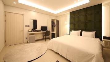 A hotel room with a bed, desk, chair, and a small table.