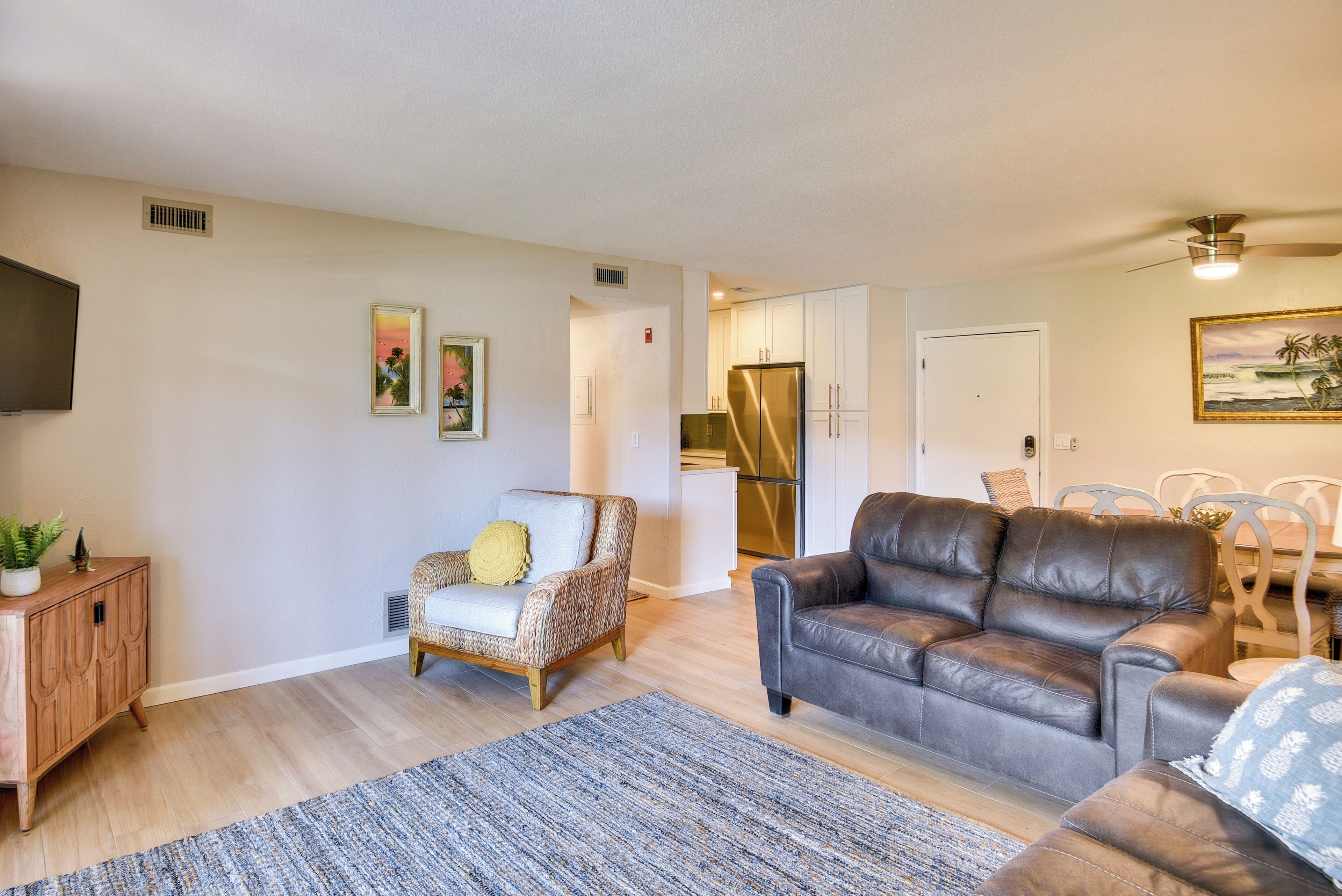 A living room with a sofa, armchair, and a dining area with chairs.