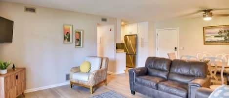 A living room with a sofa, armchair, and a dining area with chairs.