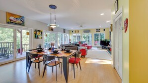 A spacious living area with a dining table, chairs, and a sofa. There are large windows and a balcony. - Charming Thornton Escape w/ Sauna + Gazebo! (Thornton)