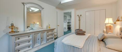 A bedroom with a large bed, a dresser, a mirror, and a door leading to a bathroom.