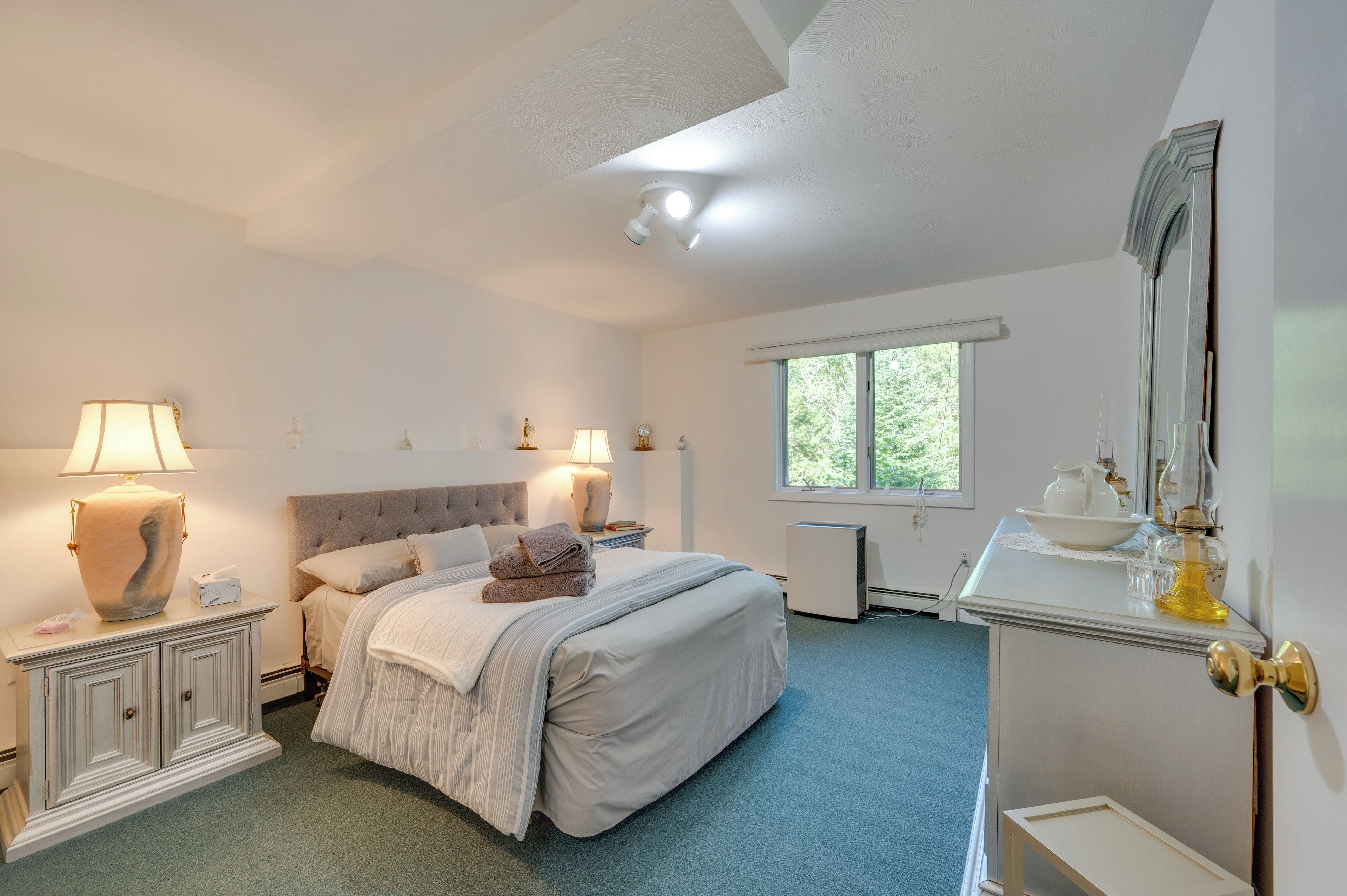 Ein Schlafzimmer mit Bett, Nachttischen, einem Schminktisch und einem Spiegel.