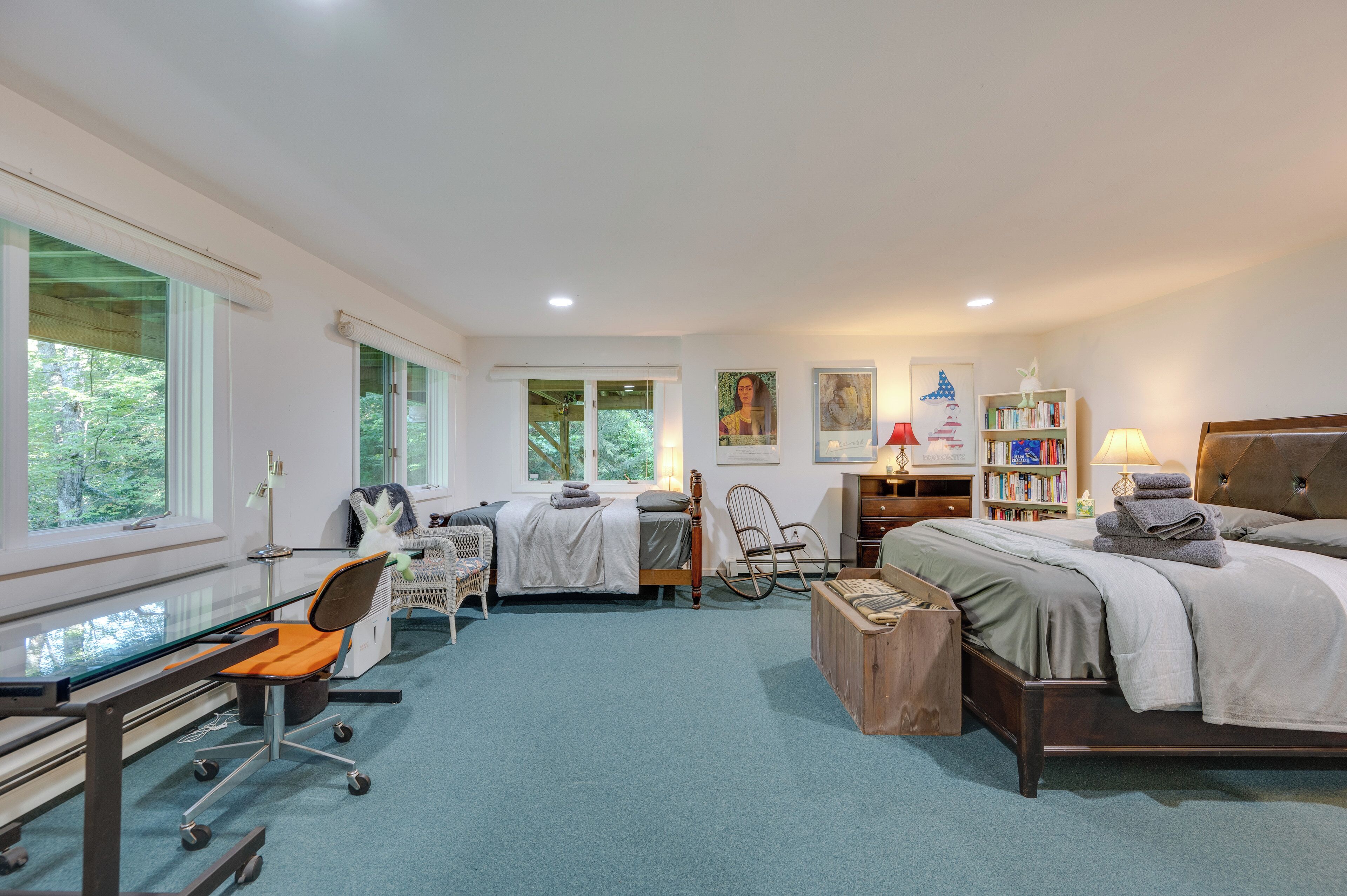 A bedroom with a desk, a bed, a chair, and a bookshelf.
