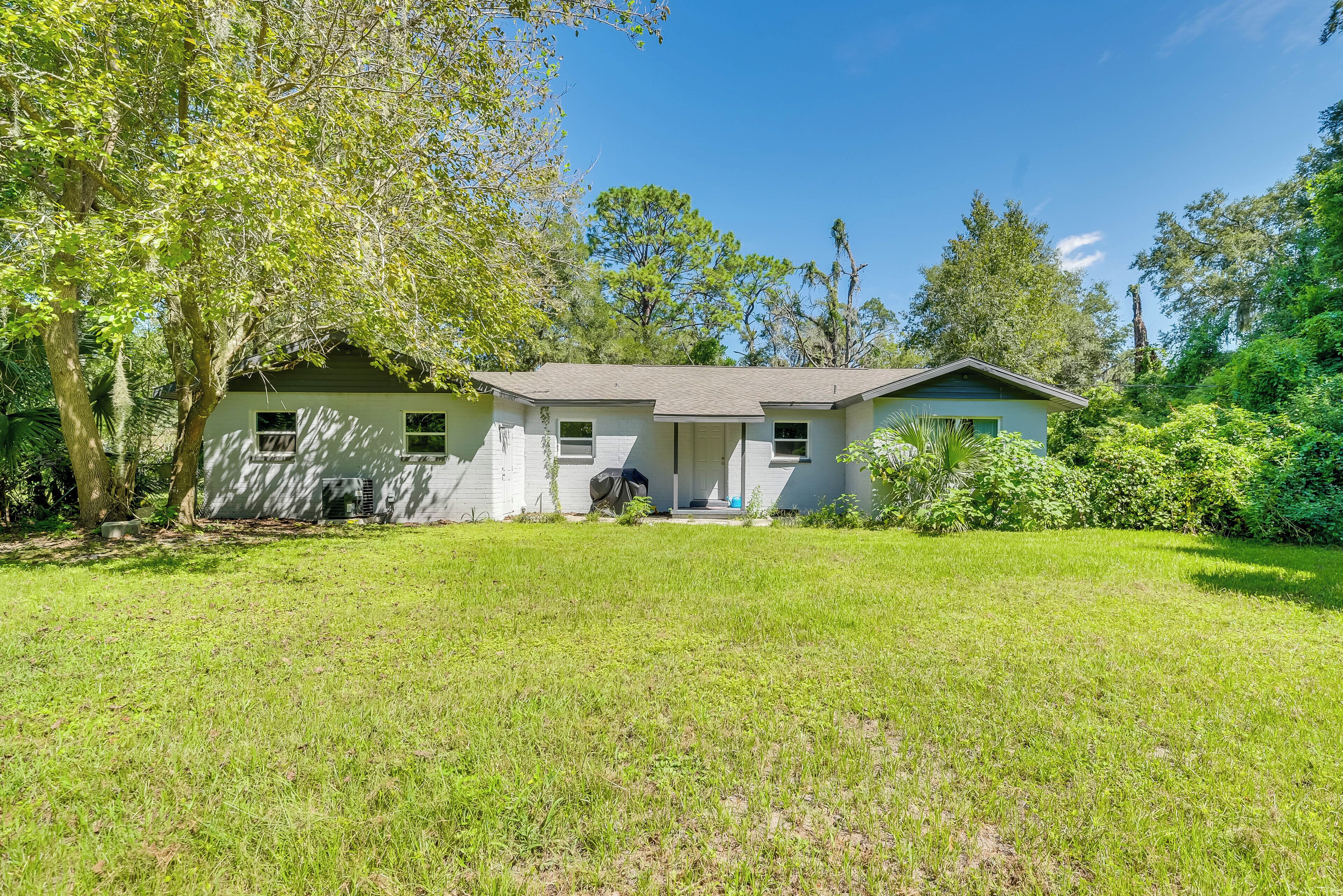 A single-story house with a front porch, surrounded by a well-maintained lawn and trees.