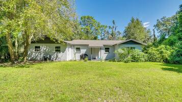 A single-story house with a front porch, surrounded by a well-maintained lawn and trees.
