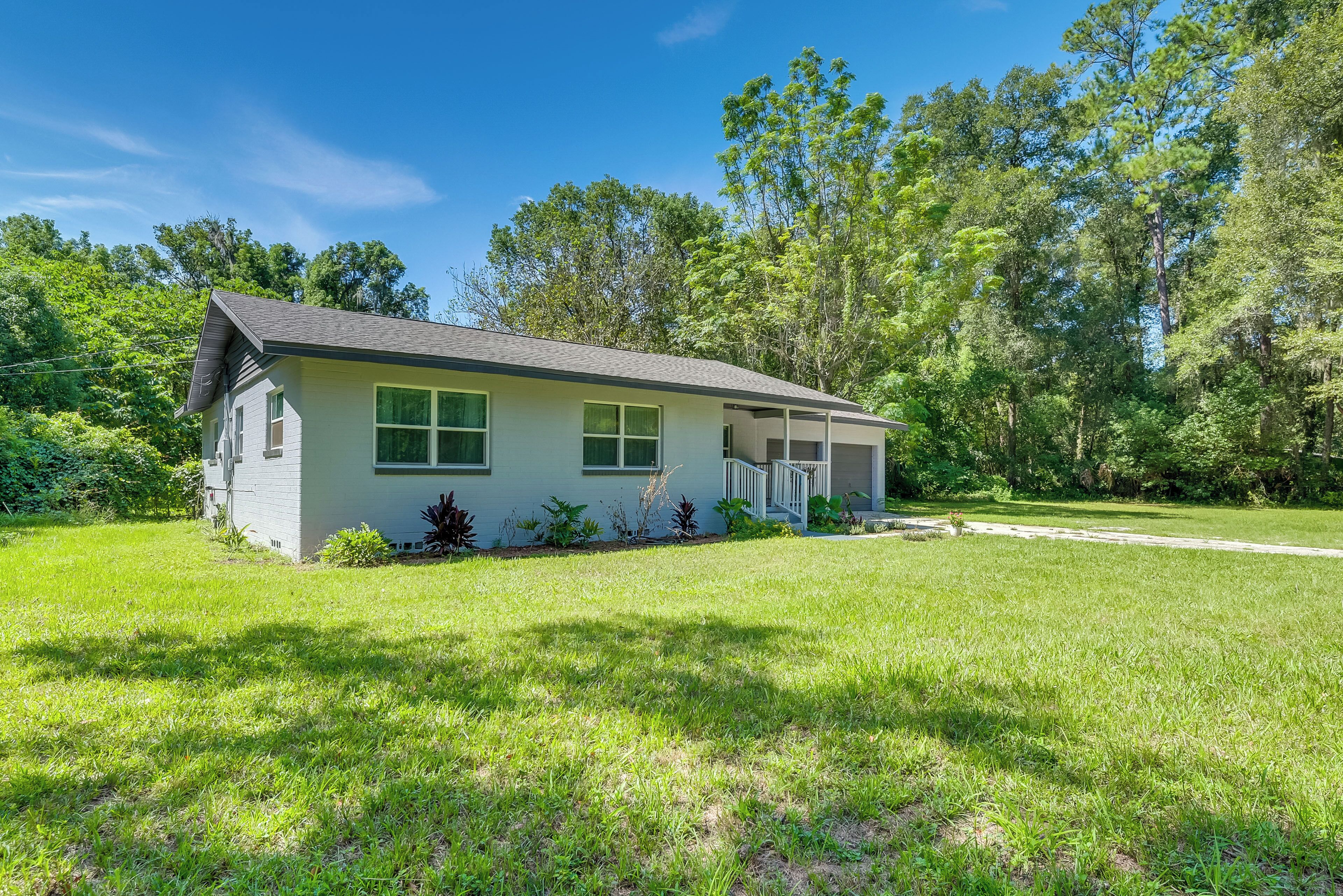 A single-story house with a front porch, surrounded by a well-maintained lawn and trees.