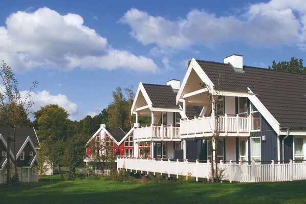 A row of traditional houses with steep roofs and white trim, set in a lush green landscape. - Großzügiges Ferienhaus in Bad Saarow (Bad Saarow)