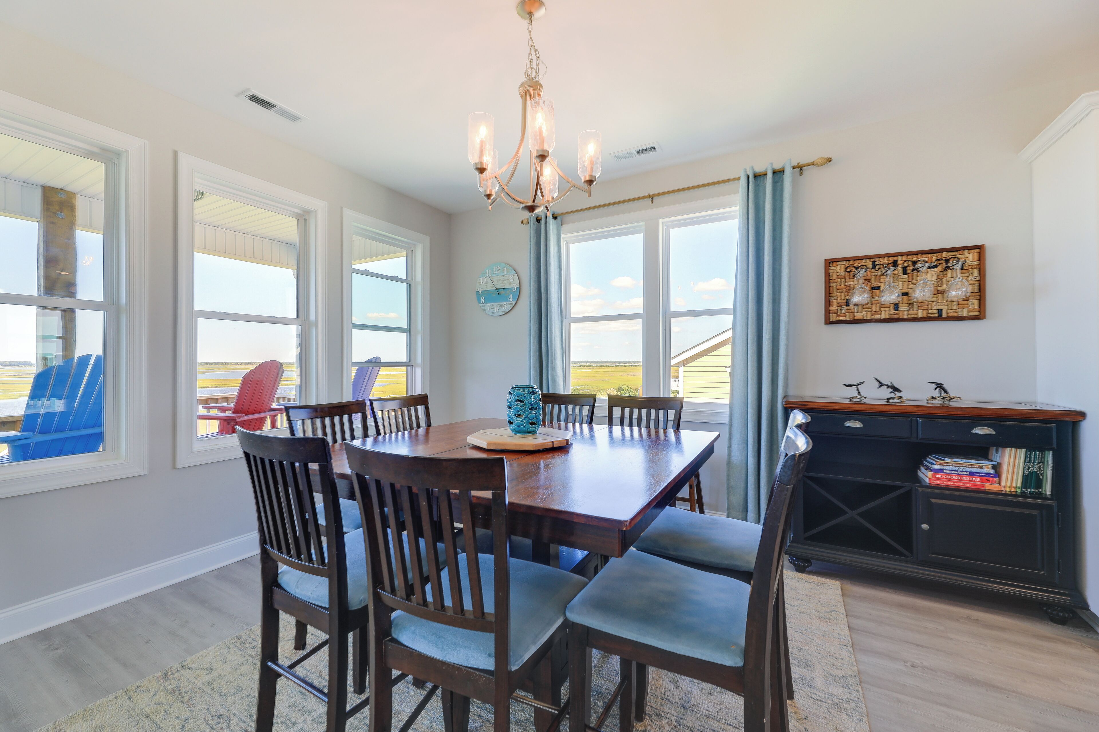 A dining area with a wooden table and chairs, a chandelier, and a view of the outdoors.