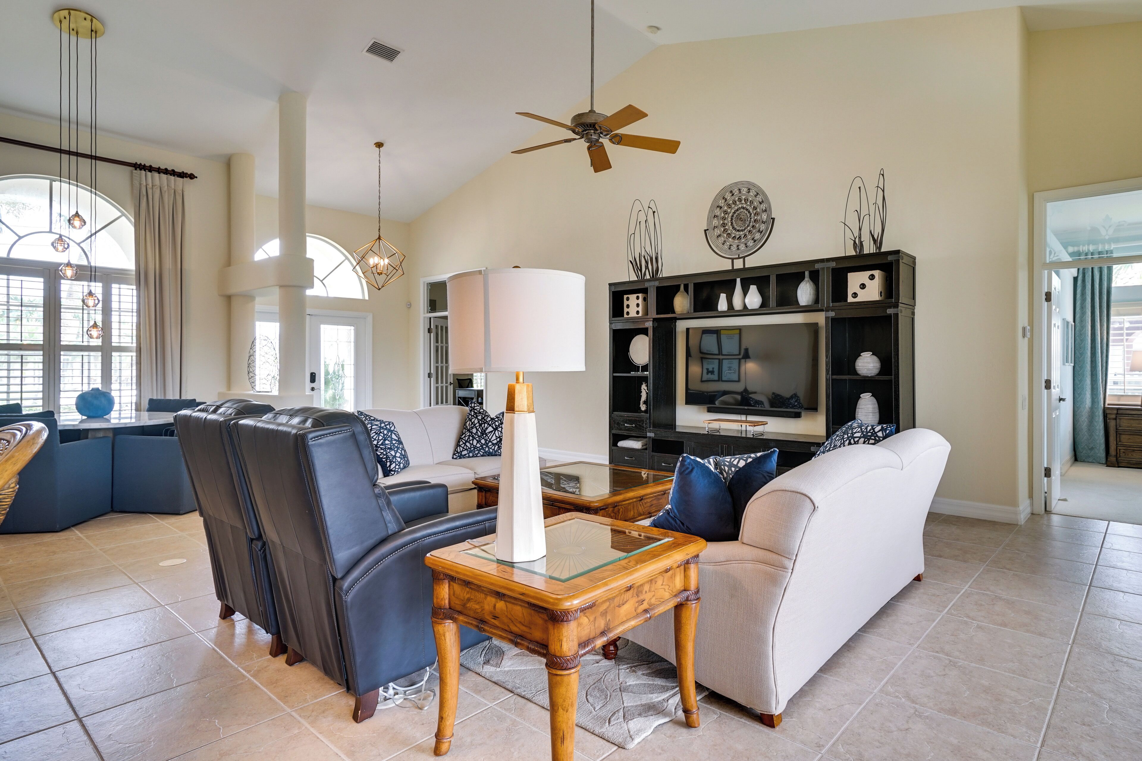 A spacious living room with a sectional sofa, a glass-top coffee table, and a television.