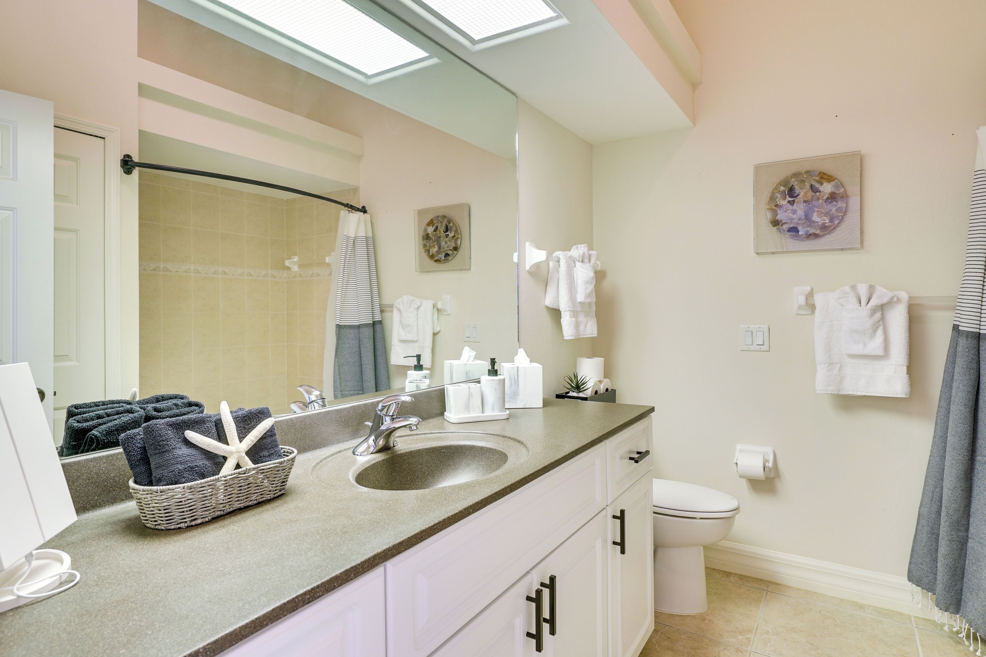 A bathroom with a sink, mirror, and towel rack. There are towels hanging on the wall and a basket with towels on the counter.