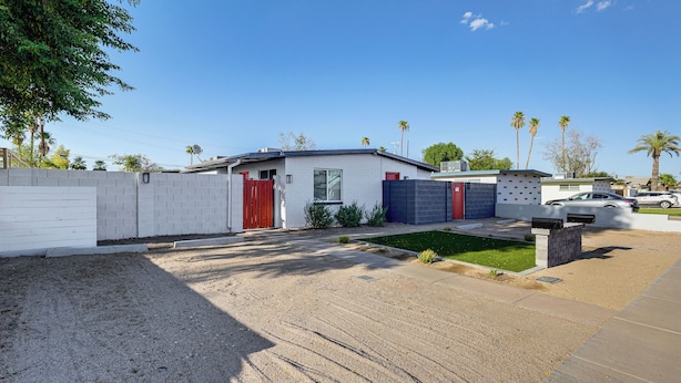 A residential property with a fenced yard, a small lawn, and a driveway leading to a garage.
