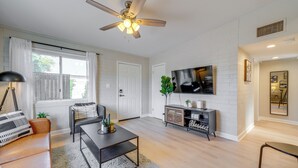 A modern living room with a sofa, coffee table, TV, and a ceiling fan.