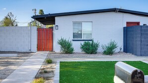 A modern house with a red door, a small window, and a mailbox in the front yard.