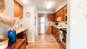Una cocina con armarios de madera, un refrigerador de acero inoxidable y un microondas.