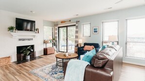 Una sala de estar con chimenea, televisor, sofá y vistas a través del ventanal.