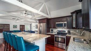 A modern kitchen with dark wood cabinets, stainless steel appliances, and a granite countertop. - Captain House (Summerland Key)