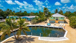 A resort with a swimming pool, palm trees, and beachside cabanas. - Captain House (Summerland Key)