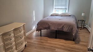 A bedroom with a bed, a dresser, and a lamp. - Historic Newport...steps to downtown/wharfs dining, shopping, attractions (Newport)