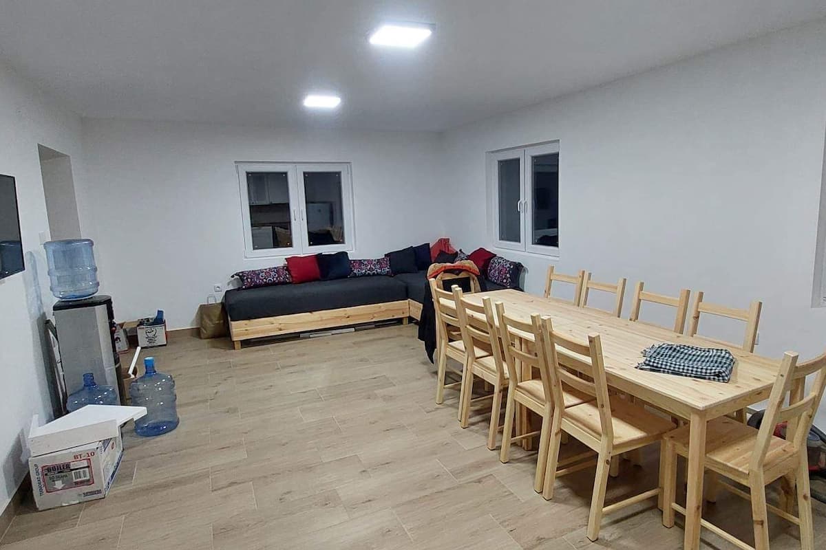 A compact living space with a dining table and chairs, a sofa, and a TV mounted on the wall.