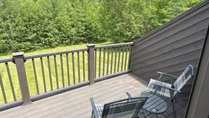 A deck with a railing, two metal chairs, and a table. - Steps to Sherburne Base Lodge and Lift at Burke Mountain (Burke)