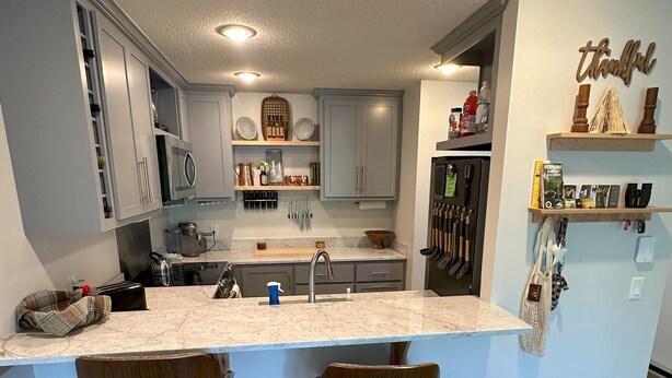 A modern kitchen with a central island, bar stools, and a refrigerator with a wine cooler. - Steps to Sherburne Base Lodge and Lift at Burke Mountain (Burke)