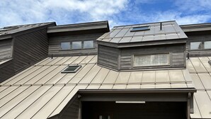 A modern building with a sloped roof, a garage, and a small porch area. - Steps to Sherburne Base Lodge and Lift at Burke Mountain (Burke)