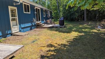 A blue house with a deck, outdoor seating, and a grill.