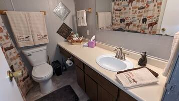 A bathroom with a toilet, sink, and mirror. There are towels with 'Live. Love. Lodge.' printed on them.