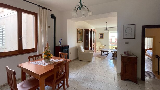 A spacious living area with a dining table, chairs, a sofa, and a chair. There is a staircase leading to another level.