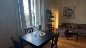 Een woonkamer met een bank, een eettafel met stoelen, een salontafel en een potplant.