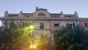 Een gebouw met een symmetrische gevel, boogvormige deuropeningen en een balkon op de bovenverdieping.