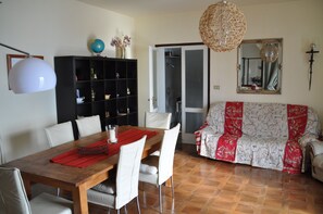 Un coin repas avec une table en bois, des chaises blanches, un set de table rouge et un globe posé sur une étagère.