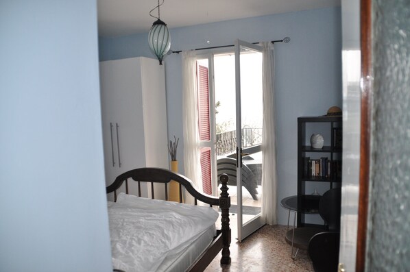 Une chambre à coucher comprenant un lit, une bibliothèque et une porte-fenêtre coulissante donnant sur un balcon.
