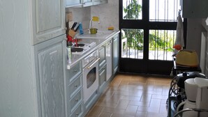 Cocina con armarios azul claro, un lavamanos y una estufa. Se ve follaje verde a través de la ventana.