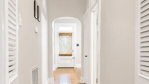 Un couloir avec un plancher en bois, des murs blancs et des portes blanches.