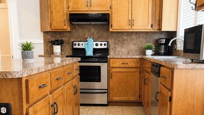 Une cuisine avec des meubles de rangement en bois, une cuisinière, un four et un four à micro-ondes.