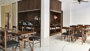 Comedor con mesas y sillas de madera, suelo de mármol y armarios empotrados de madera con electrodomésticos de cocina.