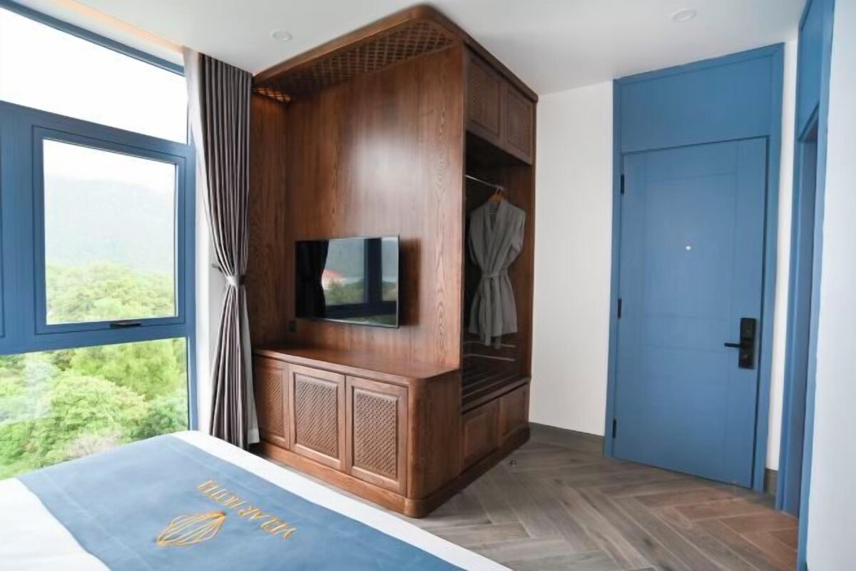 Un dormitorio con cama, televisor, armario y puerta.