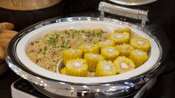 A buffet with a plate of fried rice and corn on the cob.
