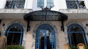 Un hotel con fachada blanca, varios balcones y una entrada azul.