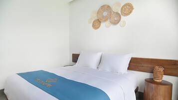 A neatly made bed with a blue and white bedspread, a wooden headboard, and a decorative wall hanging.