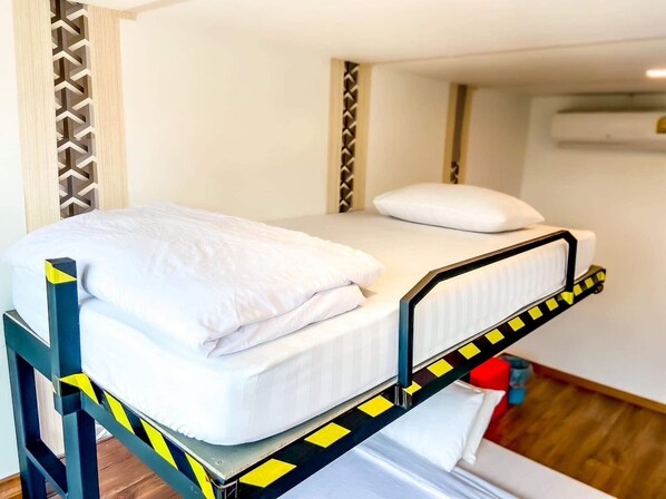 A bunk bed with a mattress and pillows, a headboard with a geometric pattern, and an air conditioning unit on the wall.