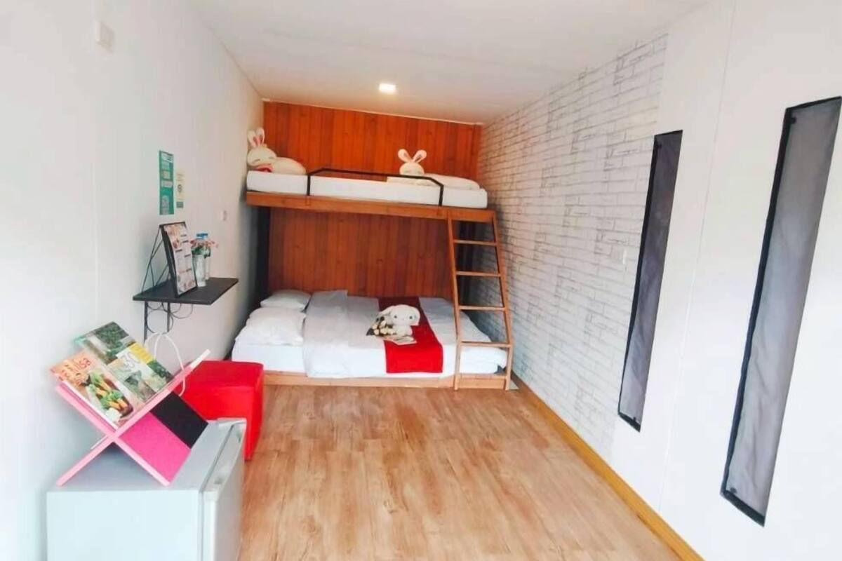 A compact room with a bunk bed, a small desk with a chair, and a shelving unit.