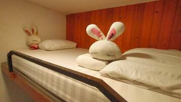 Una cama con un almohadón blanco, un conejo de peluche y un peluche más pequeño.